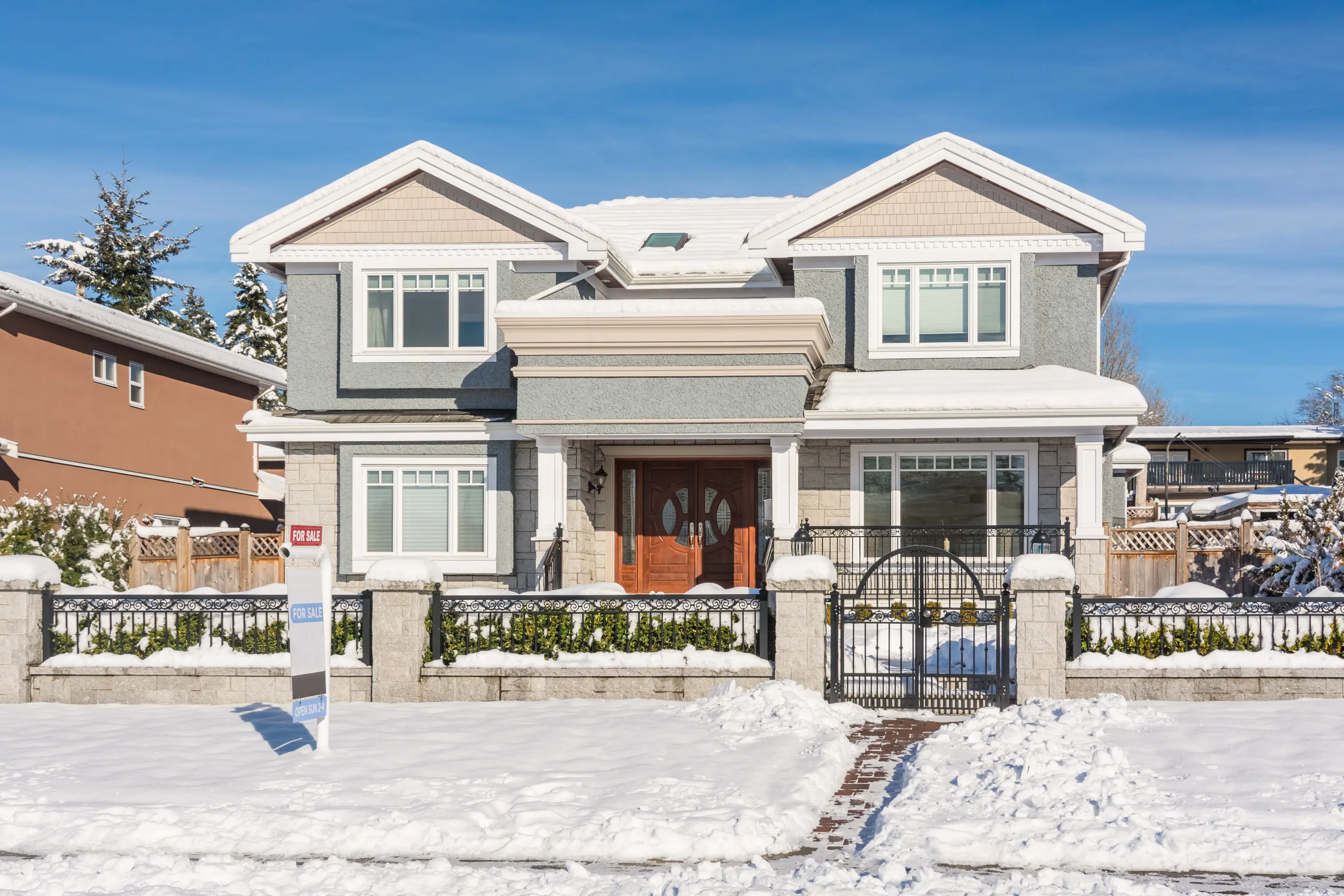 A high-end residential house with a snow-covered front yard on a sunny winter day.